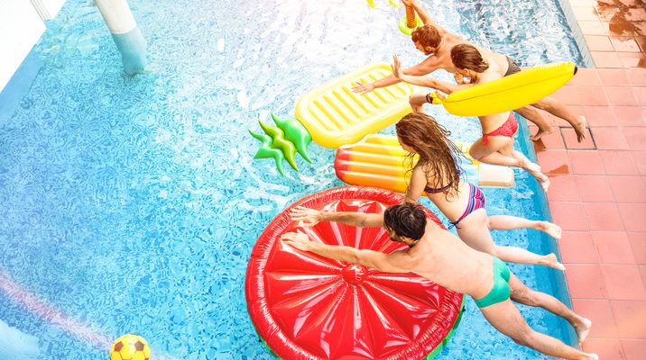 Top view of active friends jumping at swimming pool party – Vacation concept with happy guys and girls having fun in summer day at luxury resort – Dynamic young people on warm bright sunshine filter